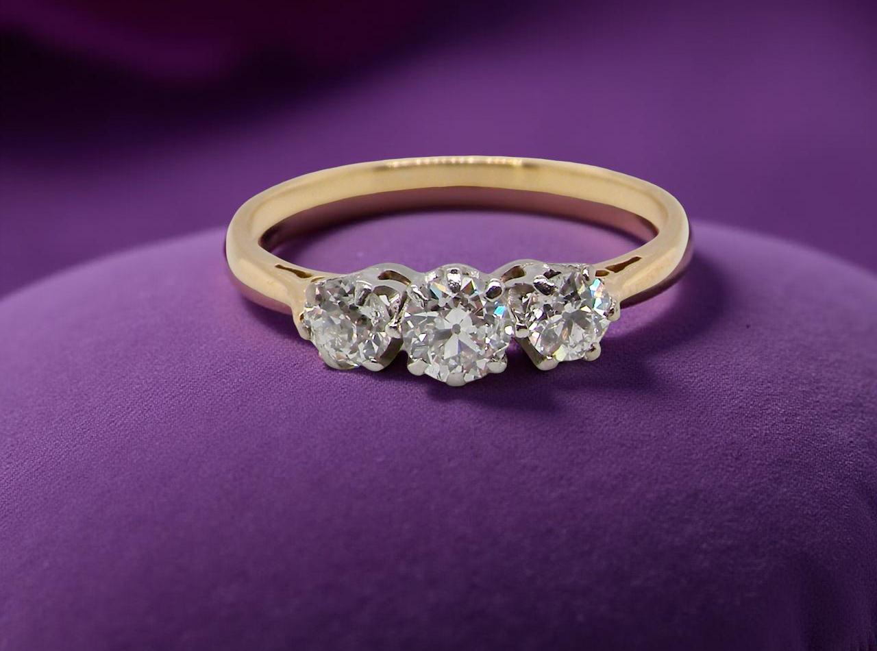 Gold ring with three diamonds on a purple background