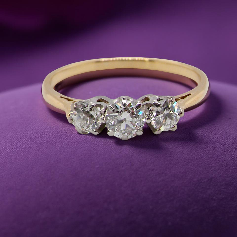Gold ring with three diamonds on a purple background