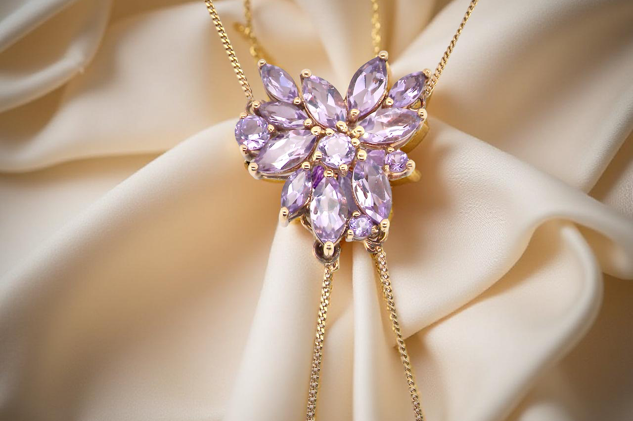 Purple gemstone necklace on a beige fabric background