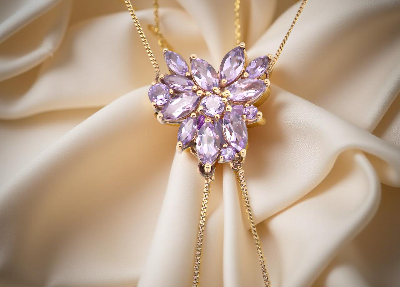 Purple gemstone necklace on a beige fabric background