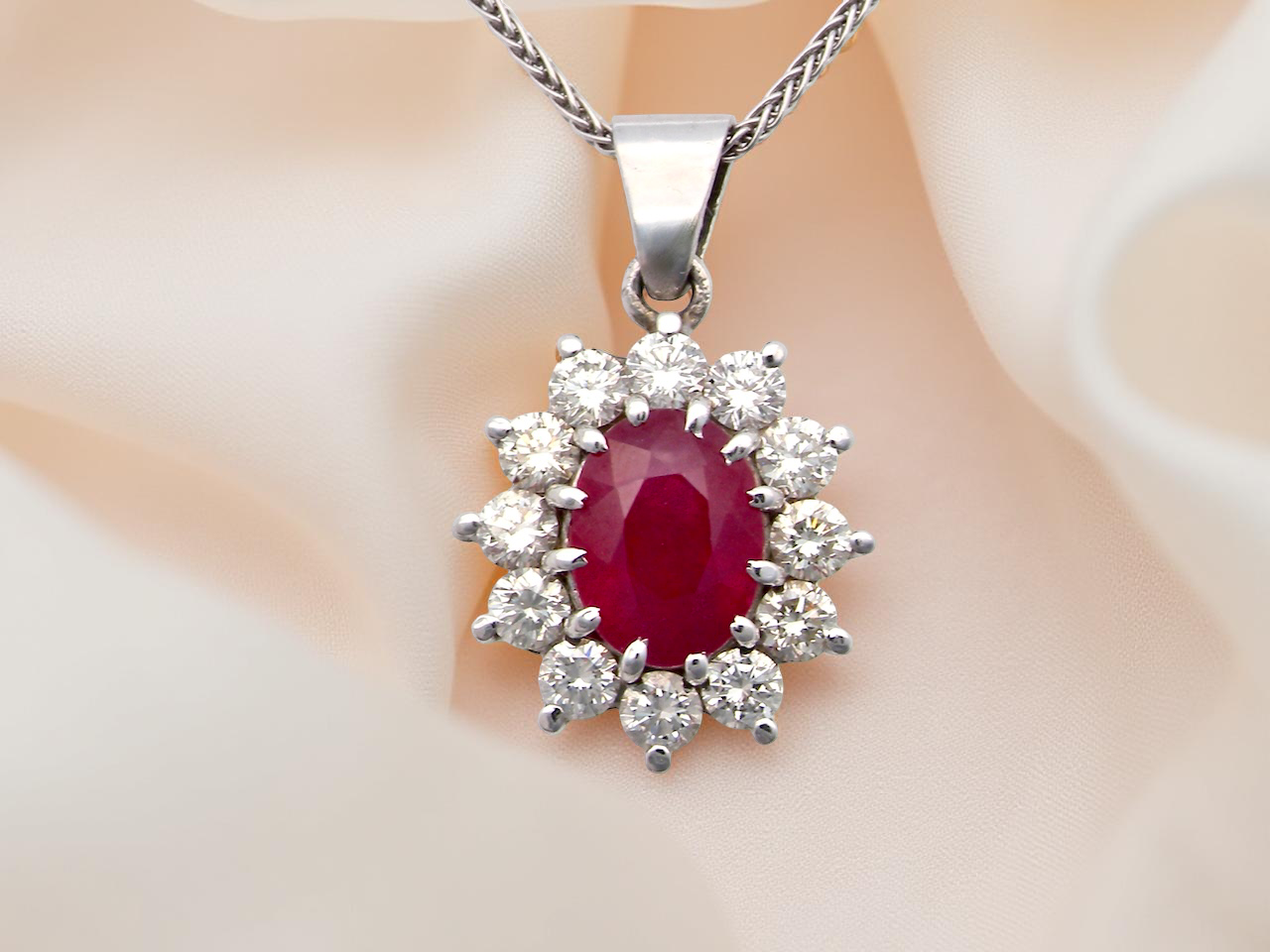 close up A striking and elegant pendant crafted in 18-carat white gold, showcasing a vibrant oval-cut ruby of approximately 2.00 carats