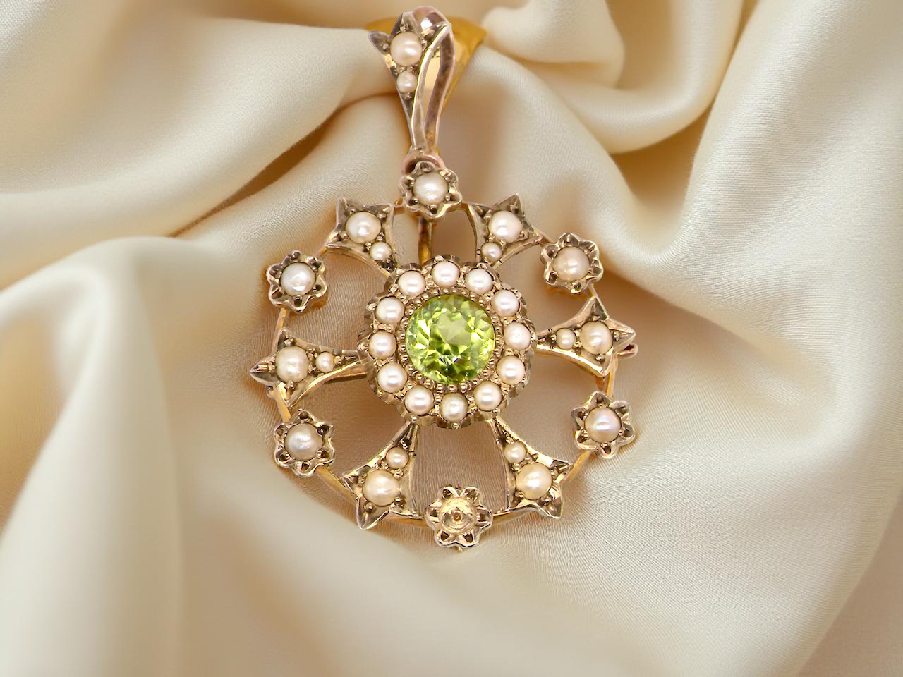 close up This exquisite piece features a 6mm peridot at its centre, framed by a delicate border of fine seed pearls.