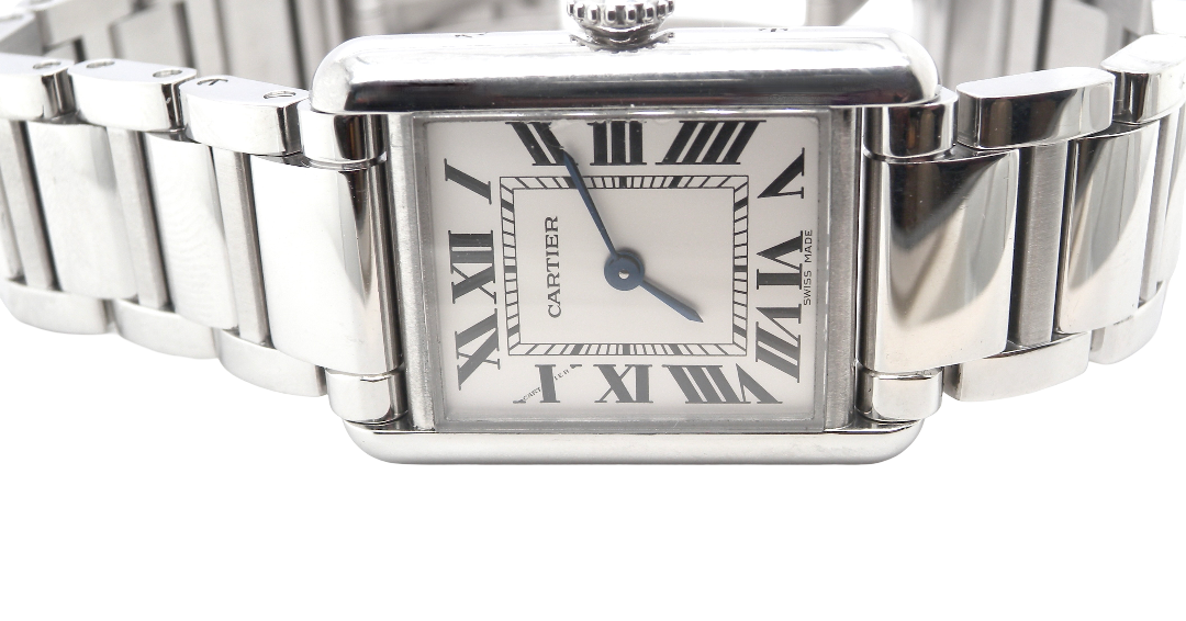 close view A womans stainless steel Cartier Tank Must wrist watch. Model number WSTA0051.
Silver coloured dial with Roman Numerals. Blue steeled hands. Case measures 29.5x22mm, case thickness 6.6mm. Quartz movement, synthetic sapphire button.