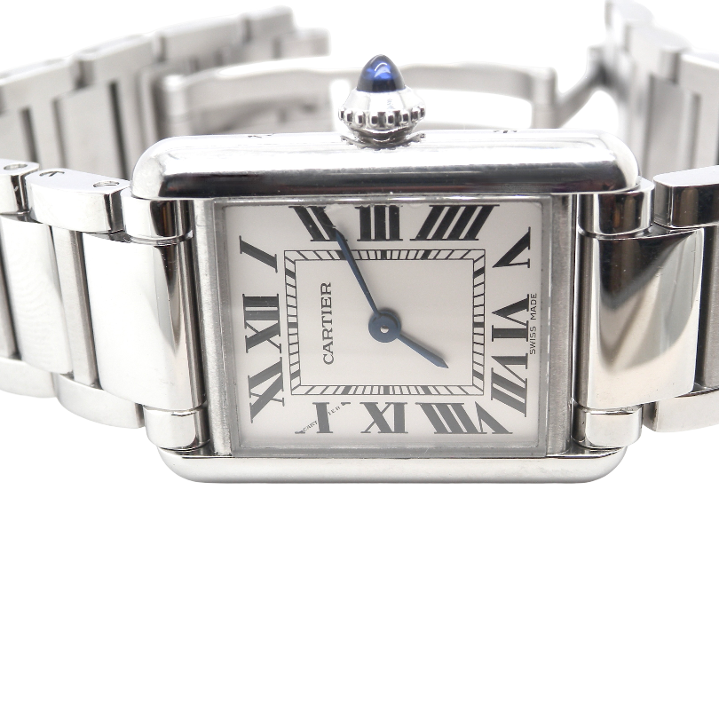 close view A womans stainless steel Cartier Tank Must wrist watch. Model number WSTA0051.
Silver coloured dial with Roman Numerals. Blue steeled hands. Case measures 29.5x22mm, case thickness 6.6mm. Quartz movement, synthetic sapphire button.