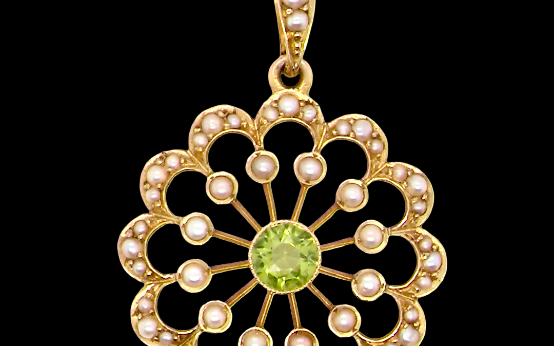 pendant from the Edwardian- Age of Elegance-
The centre stone- a round peridot 5mm diameter, mille grain set. A satellite perimeter of twelve seed pearls, each 2.4mm. The outside border is scalloped shaped and each crescent is set with tiny seed pearls.