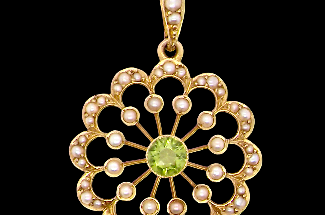 pendant from the Edwardian- Age of Elegance-
The centre stone- a round peridot 5mm diameter, mille grain set. A satellite perimeter of twelve seed pearls, each 2.4mm. The outside border is scalloped shaped and each crescent is set with tiny seed pearls.