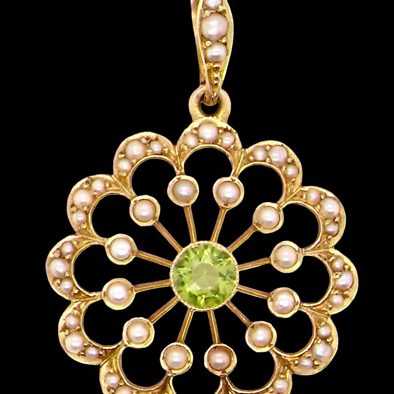 pendant from the Edwardian- Age of Elegance-
The centre stone- a round peridot 5mm diameter, mille grain set. A satellite perimeter of twelve seed pearls, each 2.4mm. The outside border is scalloped shaped and each crescent is set with tiny seed pearls.