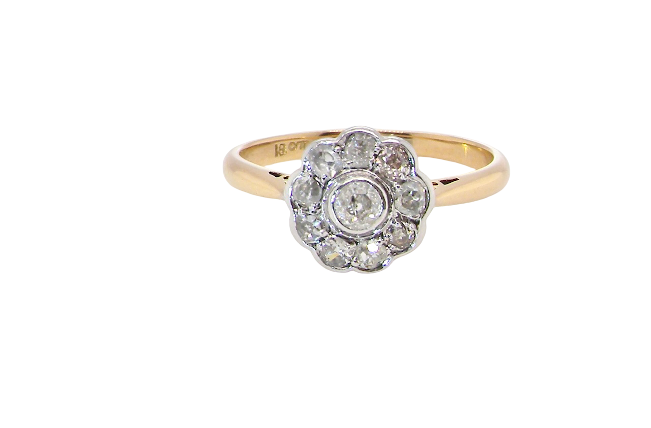 early 20th-century vintage diamond cluster ring, featuring a classic daisy-shaped head set with nine old brilliant-cut white diamonds.