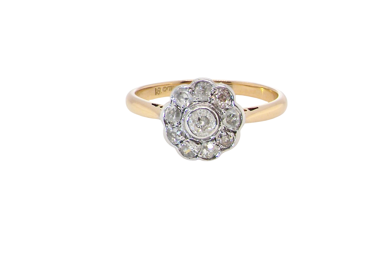 early 20th-century vintage diamond cluster ring, featuring a classic daisy-shaped head set with nine old brilliant-cut white diamonds.