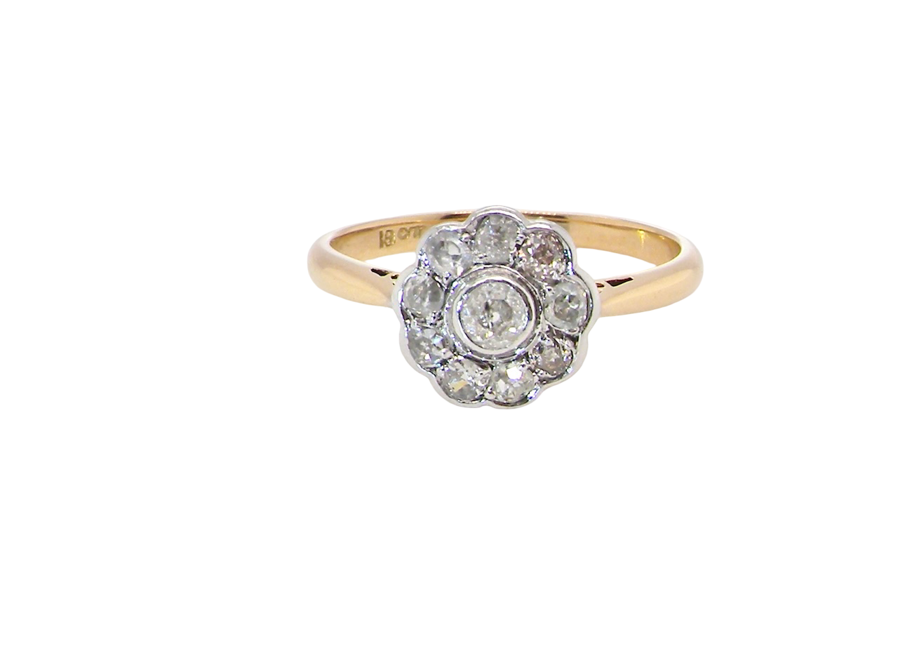 early 20th-century vintage diamond cluster ring, featuring a classic daisy-shaped head set with nine old brilliant-cut white diamonds.