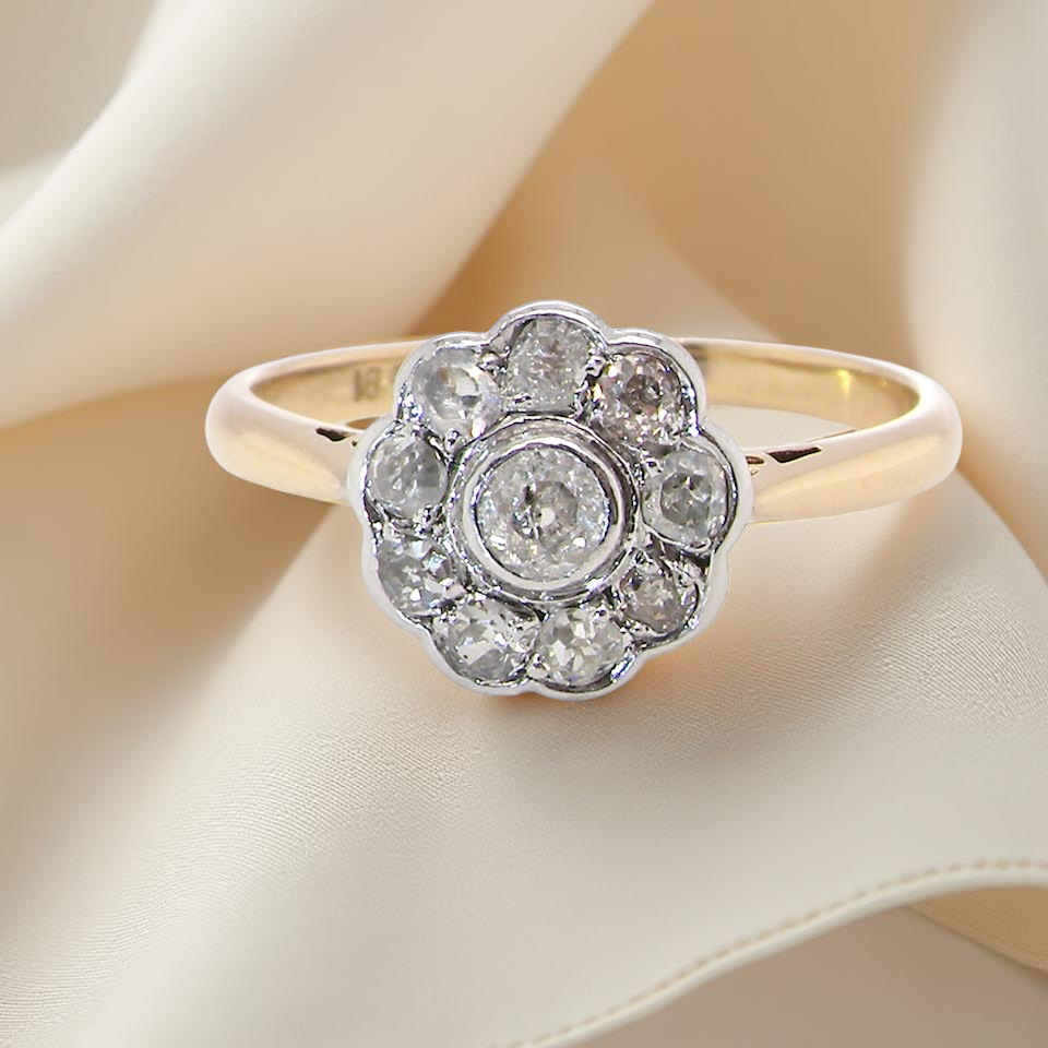 early 20th-century vintage diamond cluster ring, featuring a classic daisy-shaped head set with old brilliant-cut white diamonds.