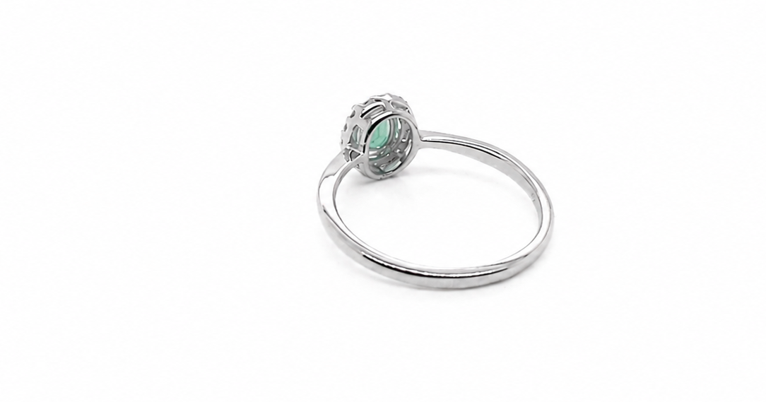 white gold ring with a green gemstone on a white background reverse image