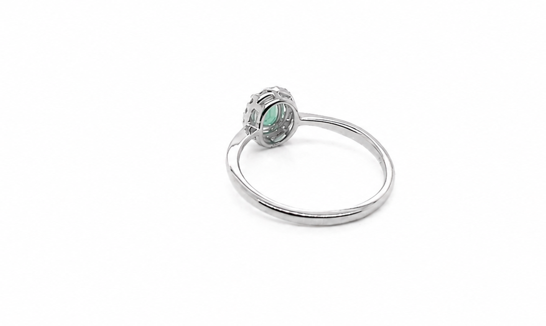 white gold ring with a green gemstone on a white background reverse image