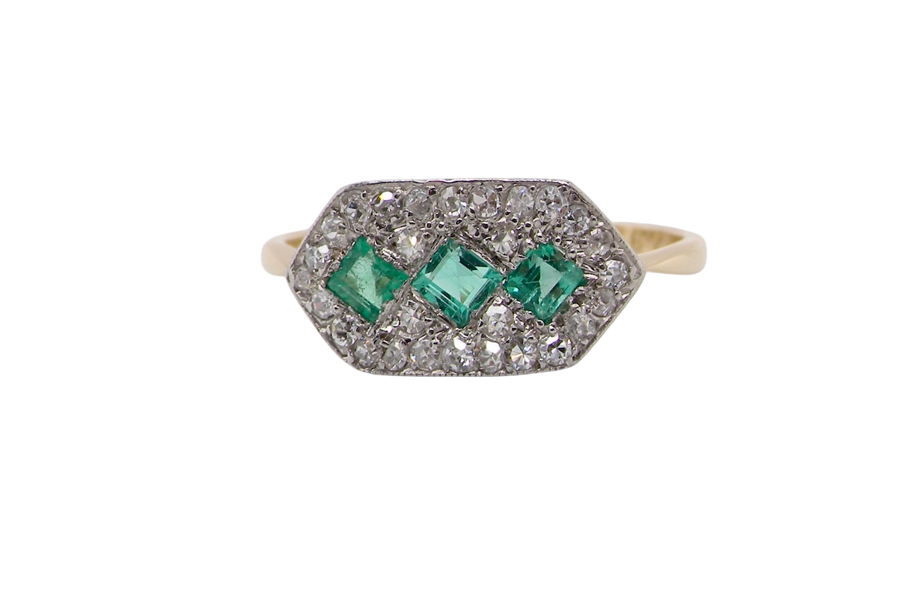 fine Edwardian era cluster ring, beautifully handcrafted with a trio of vibrant emeralds surrounded by a halo of old-cut diamonds.