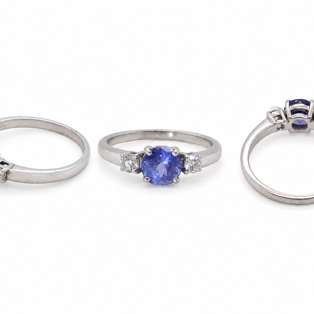 group An 18 carat white gold three stone ring. Centre stone a round tanzanite 6mm diameter.
Each side a brilliant cut white diamond