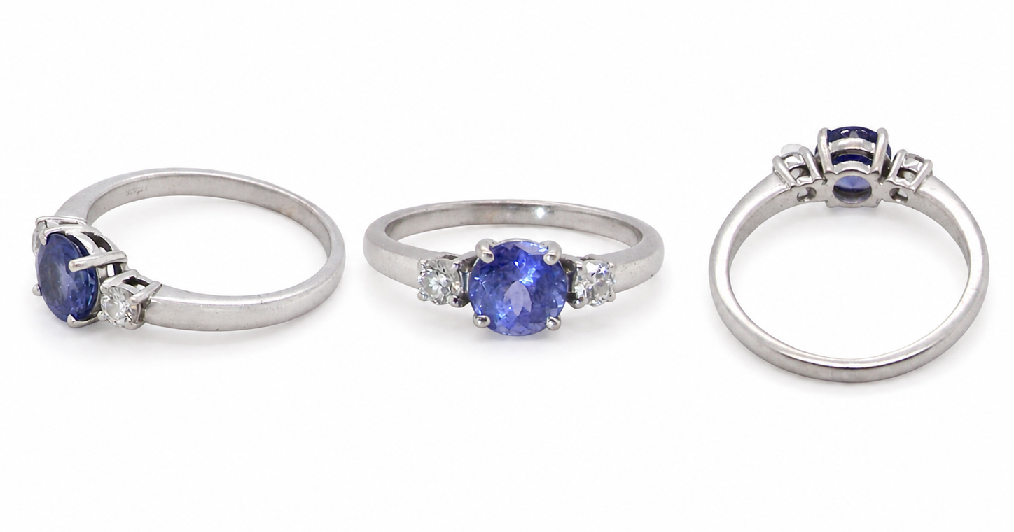 group An 18 carat white gold three stone ring. Centre stone a round tanzanite 6mm diameter.
Each side a brilliant cut white diamond