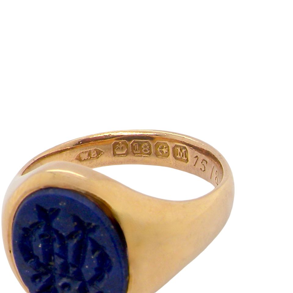 hallmarks An 18 carat gold signet ring set with an oval lapis lazuli stone. This measures 12x9.5mm and has a carved intaglio seal engraved onto the stone. (These seem to be floral patterns)