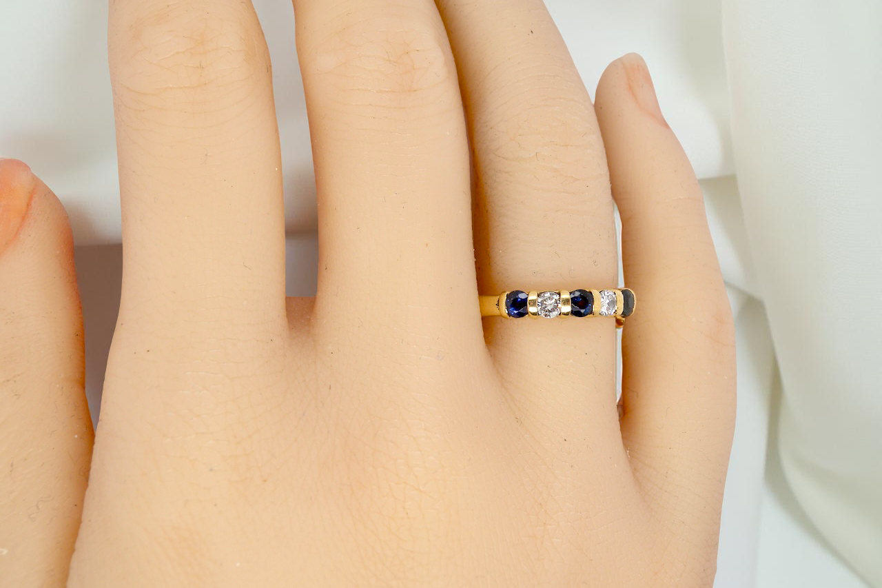 hand 18-carat gold half-hoop eternity ring, set with three round mid-blue sapphires
