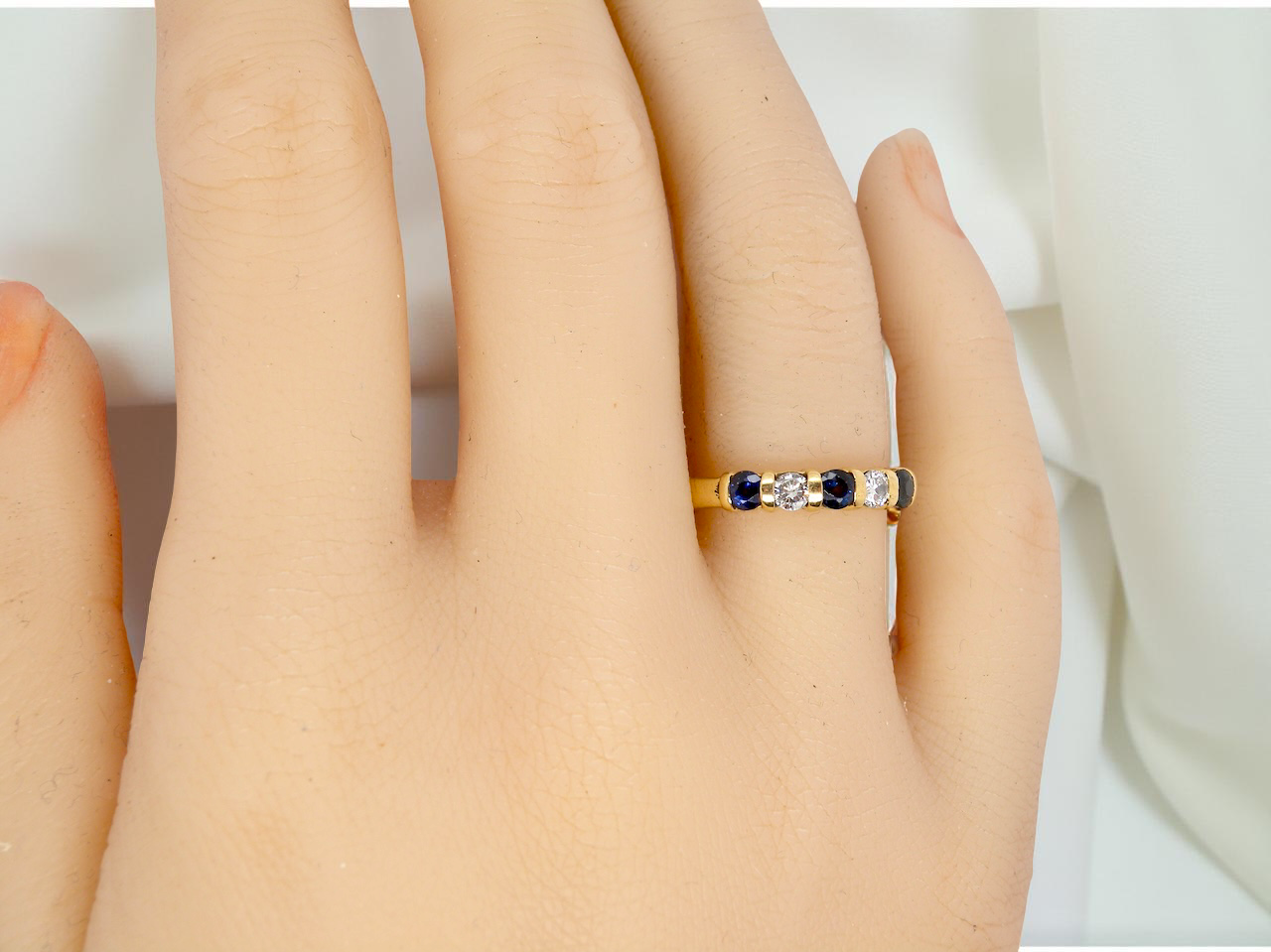 hand 18-carat gold half-hoop eternity ring, set with three round mid-blue sapphires