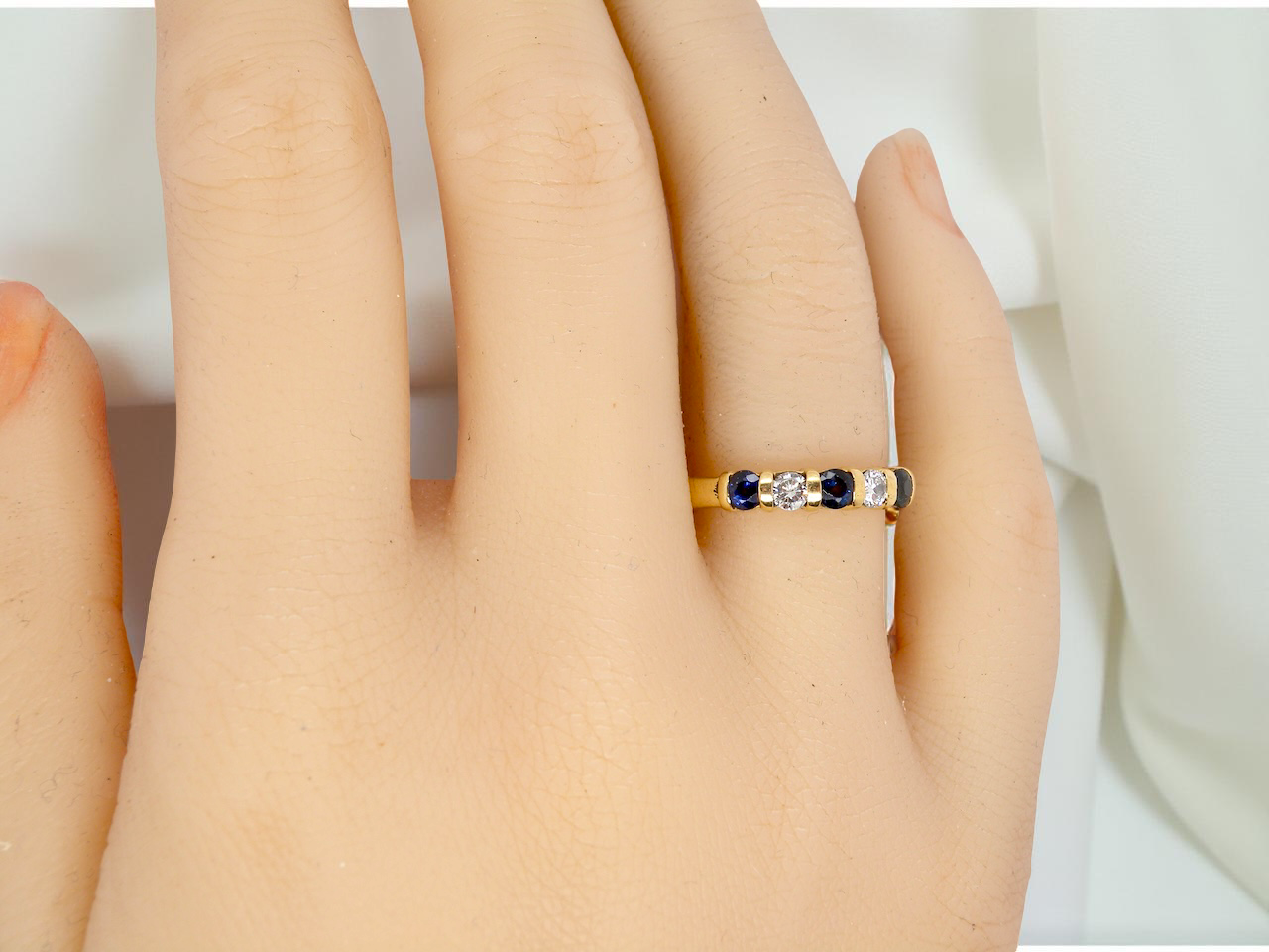 hand 18-carat gold half-hoop eternity ring, set with three round mid-blue sapphires