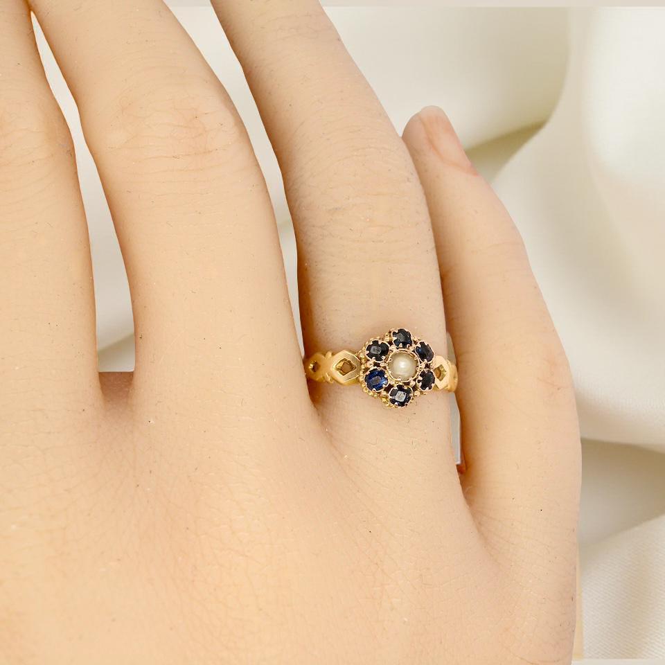 hand A 15 carat gold dress ring. The centre a small seed pearl, 3mm diameter. Surrounded by six sapphires,
