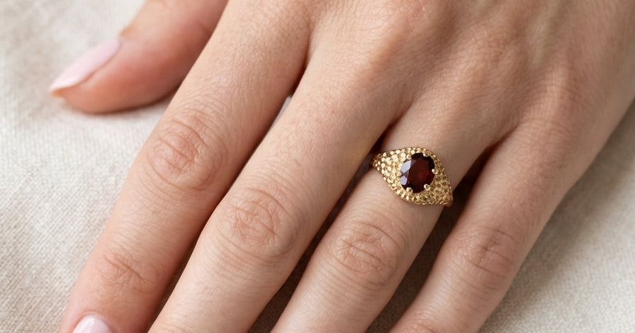 hand A 1970s dress ring set with an oval garnet stone. This measures 10x8mm and claw set.