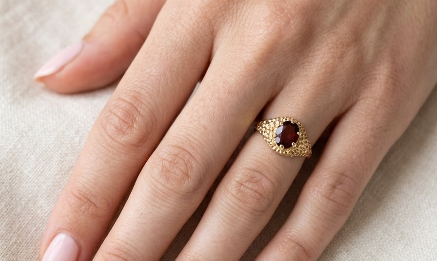 hand A 1970s dress ring set with an oval garnet stone. This measures 10x8mm and claw set.