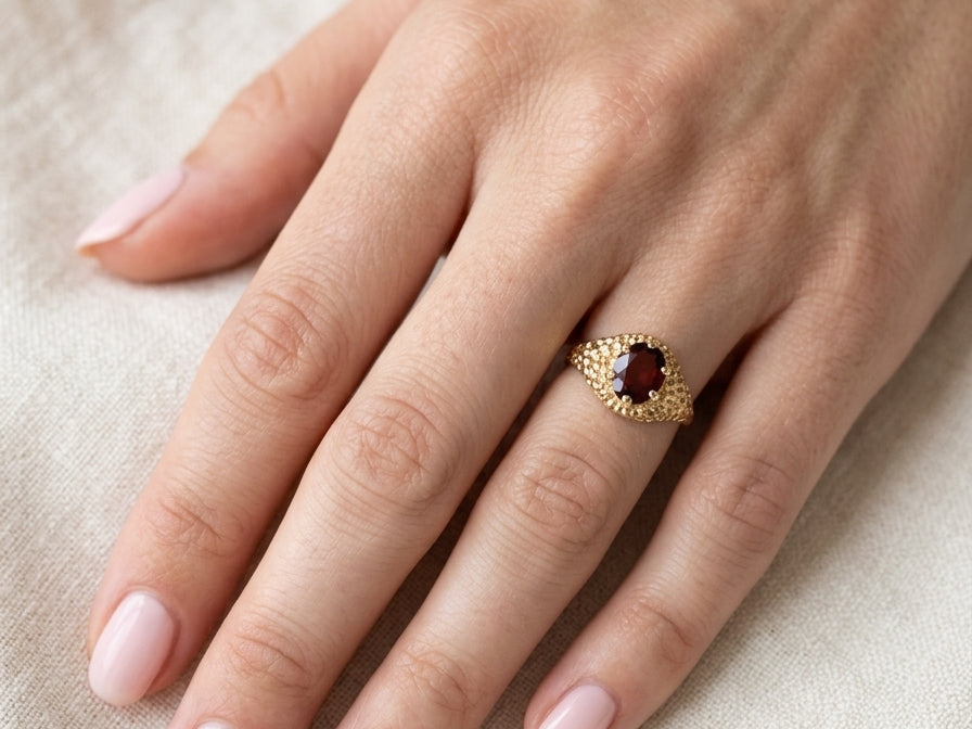 hand A 1970s dress ring set with an oval garnet stone. This measures 10x8mm and claw set.