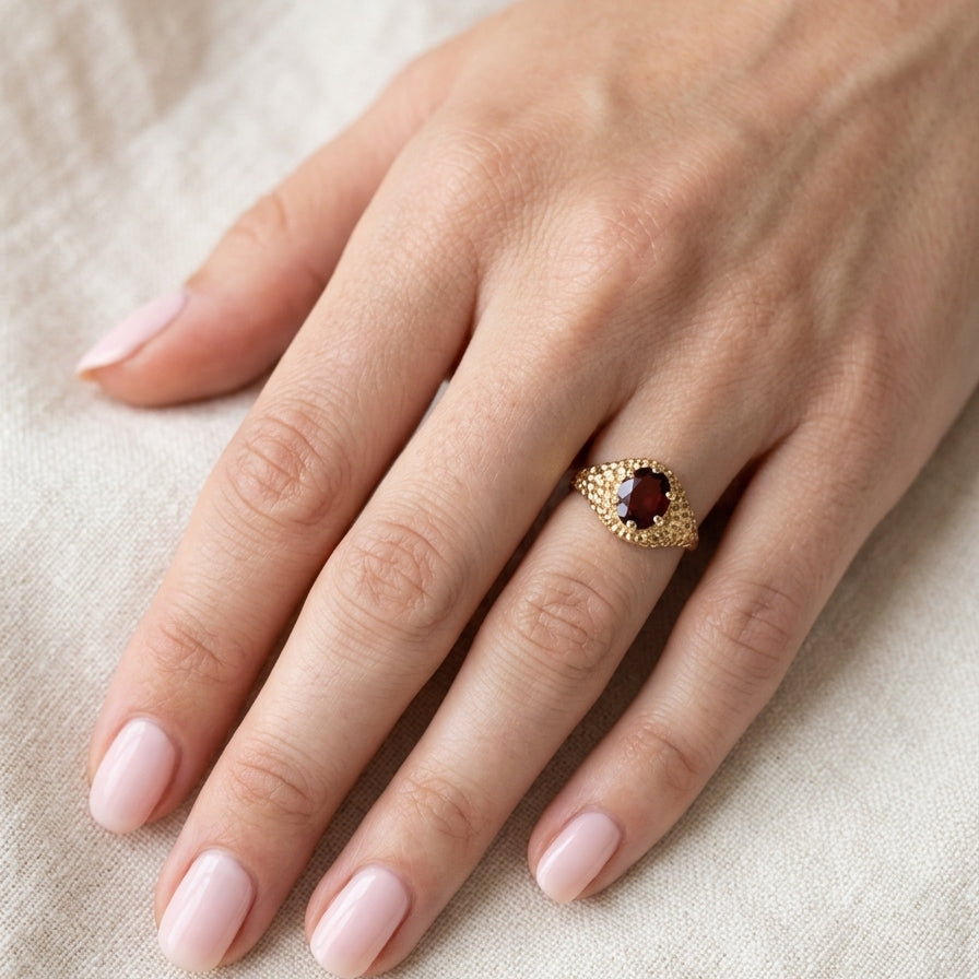 hand A 1970s dress ring set with an oval garnet stone. This measures 10x8mm and claw set.