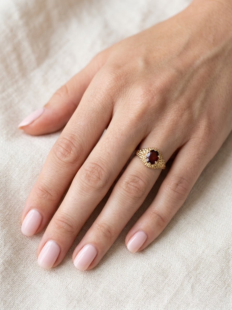 hand A 1970s dress ring set with an oval garnet stone. This measures 10x8mm and claw set.