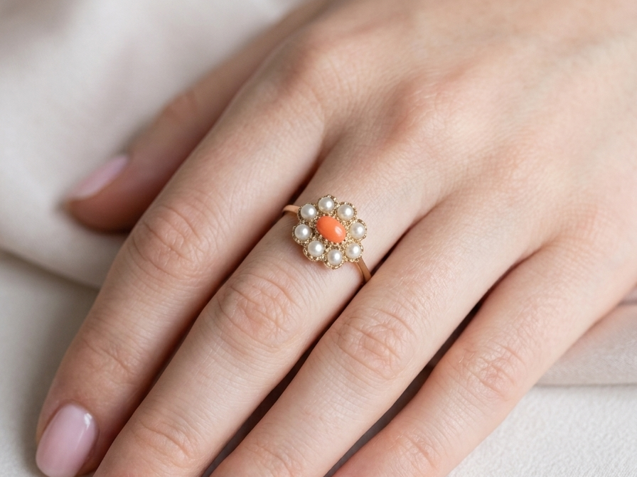 hand A 9 carat gold cluster ring. Centre stone an oval shaped coral stone 6x4mm.