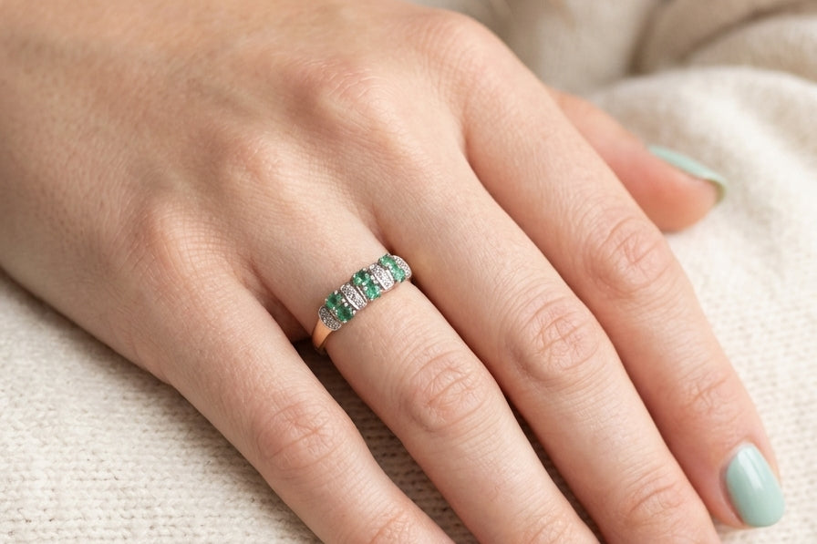 hand A 9 carat gold half hoop ring. Set with six round emeralds 3mm each,(total 0.35 carats est) and interspaced with vertical white gold sections each set with 1mm diamonds.(0.05 carats est)