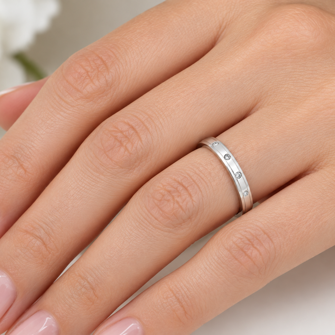 hand A 9 carat white gold wedding ring. Set with three invisbly set diamonds, each 1.5mm (0.015 carats each).