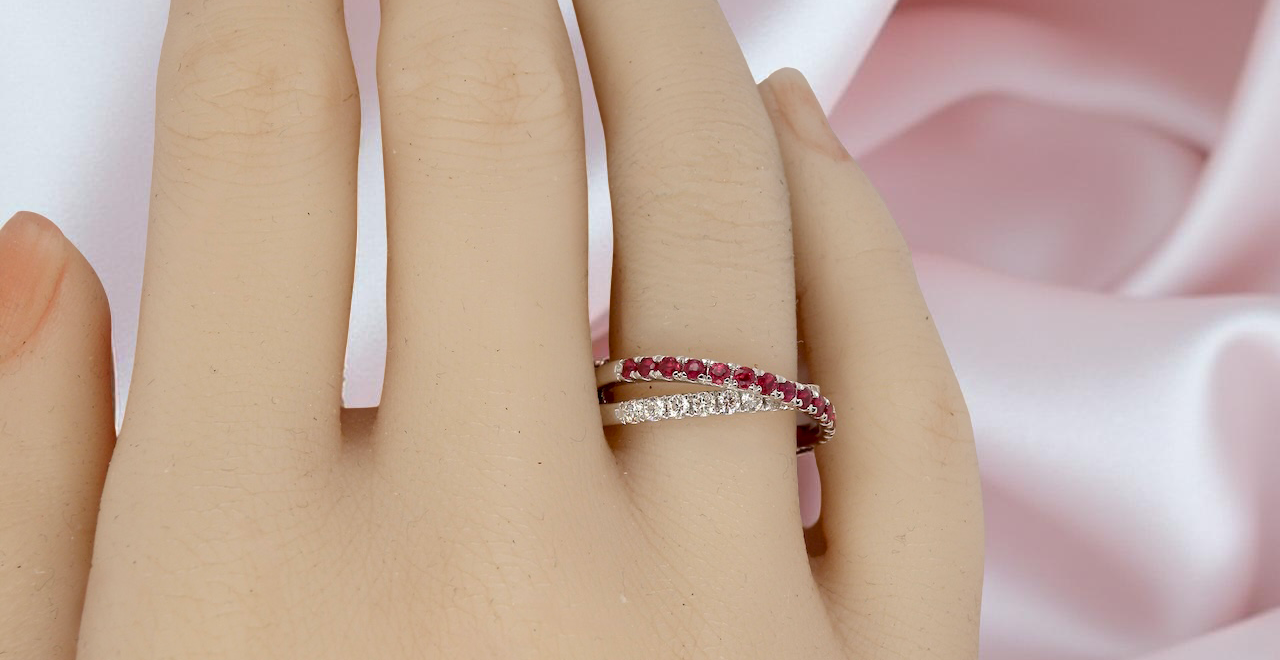 Close-up of a hand wearing two rings with a soft pink fabric background