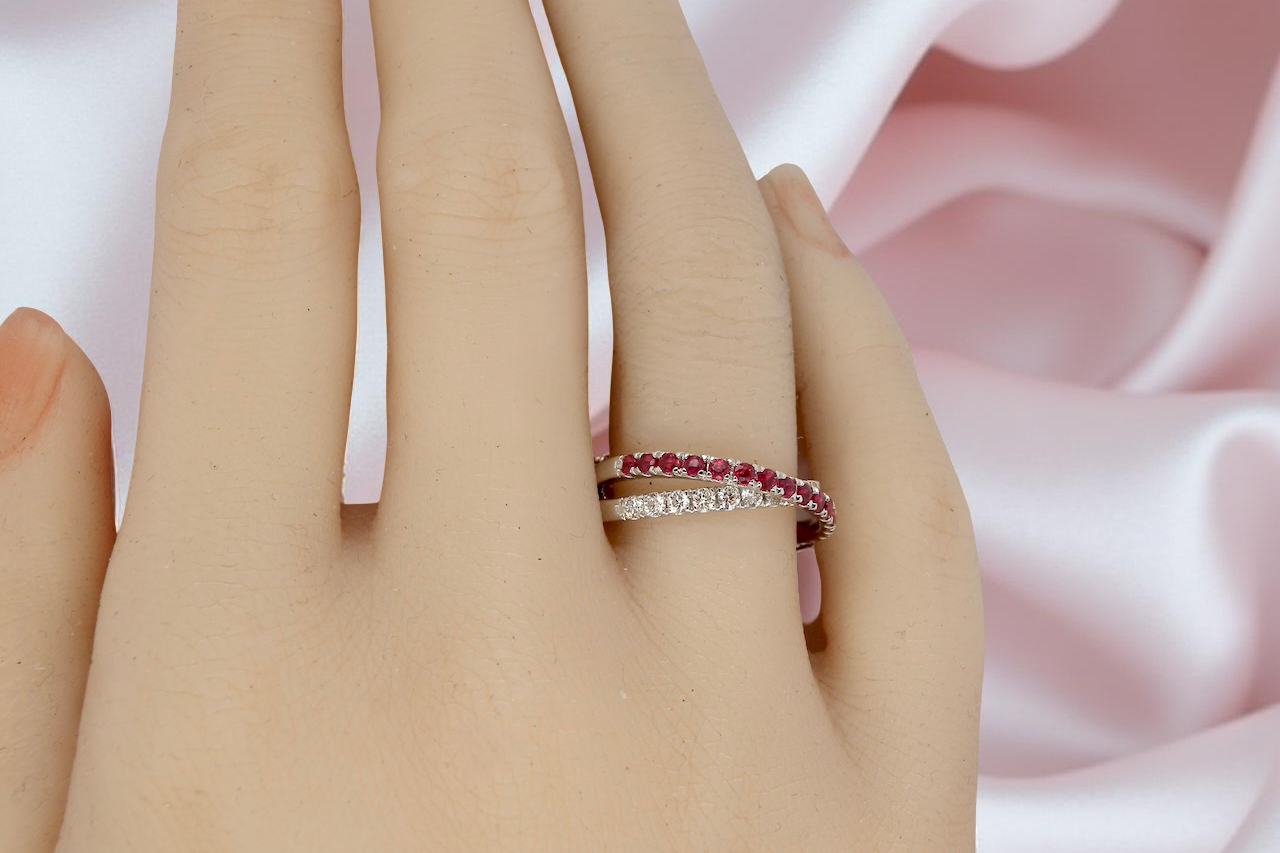Close-up of a hand wearing two rings with a soft pink fabric background