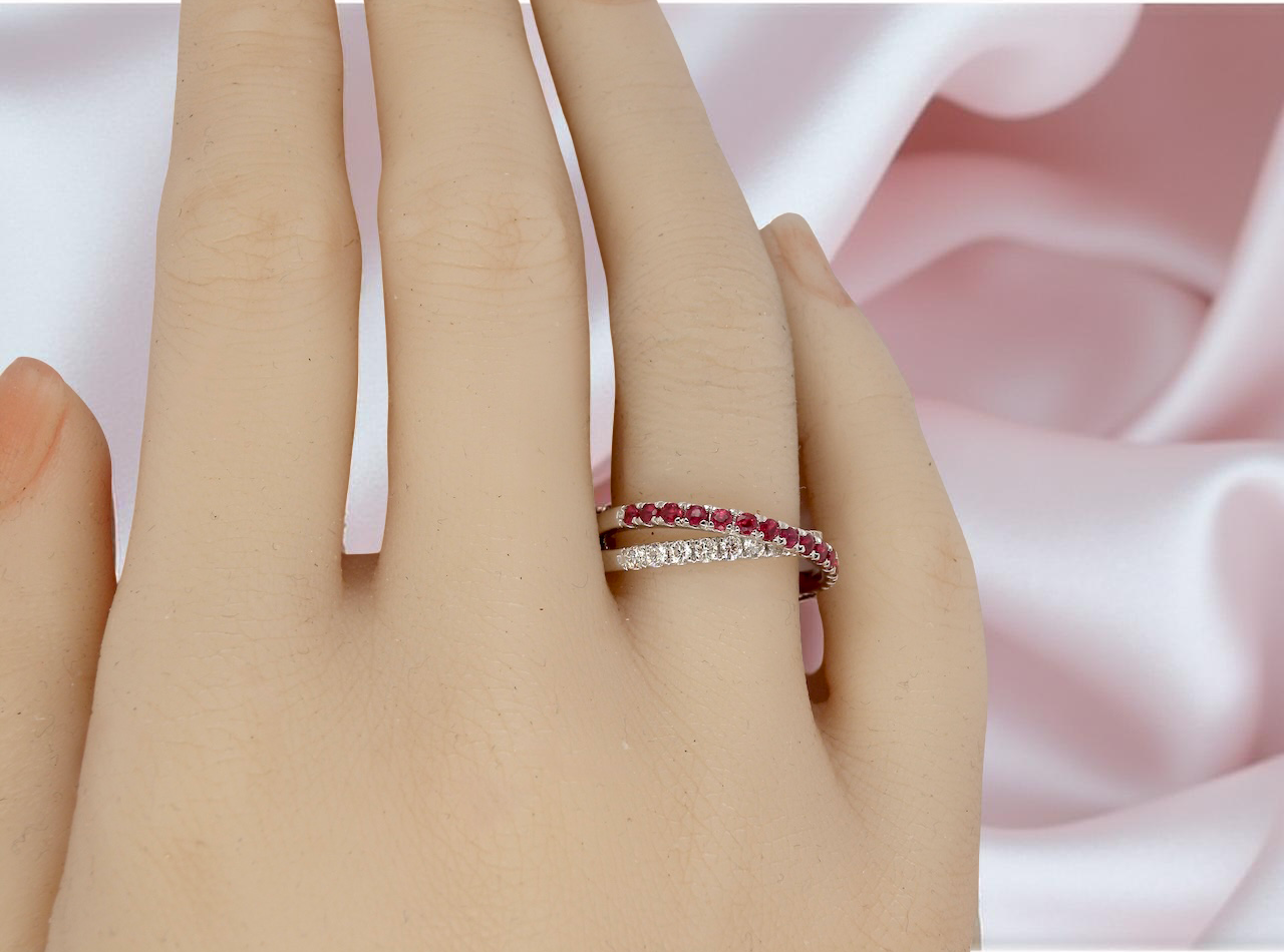 Close-up of a hand wearing two rings with a soft pink fabric background
