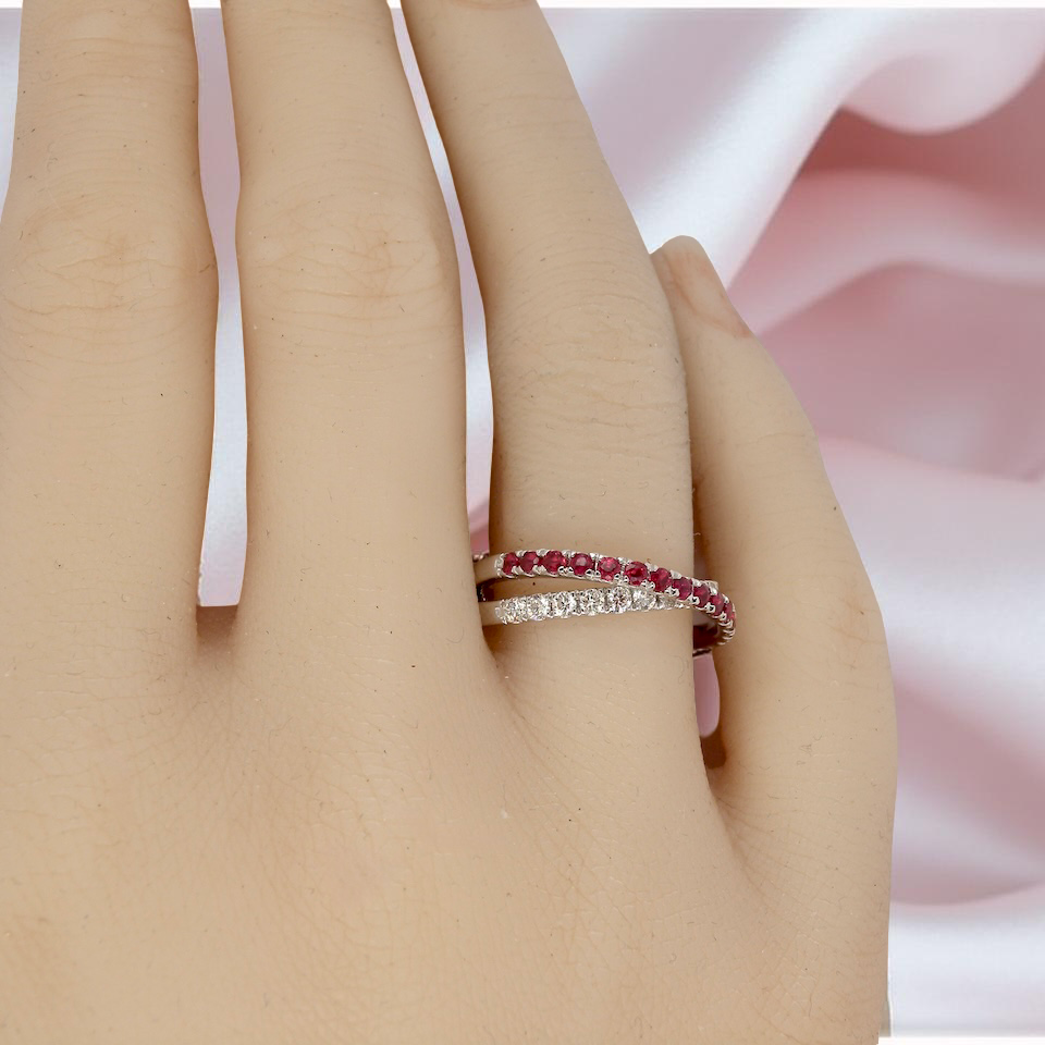 Close-up of a hand wearing two rings with a soft pink fabric background
