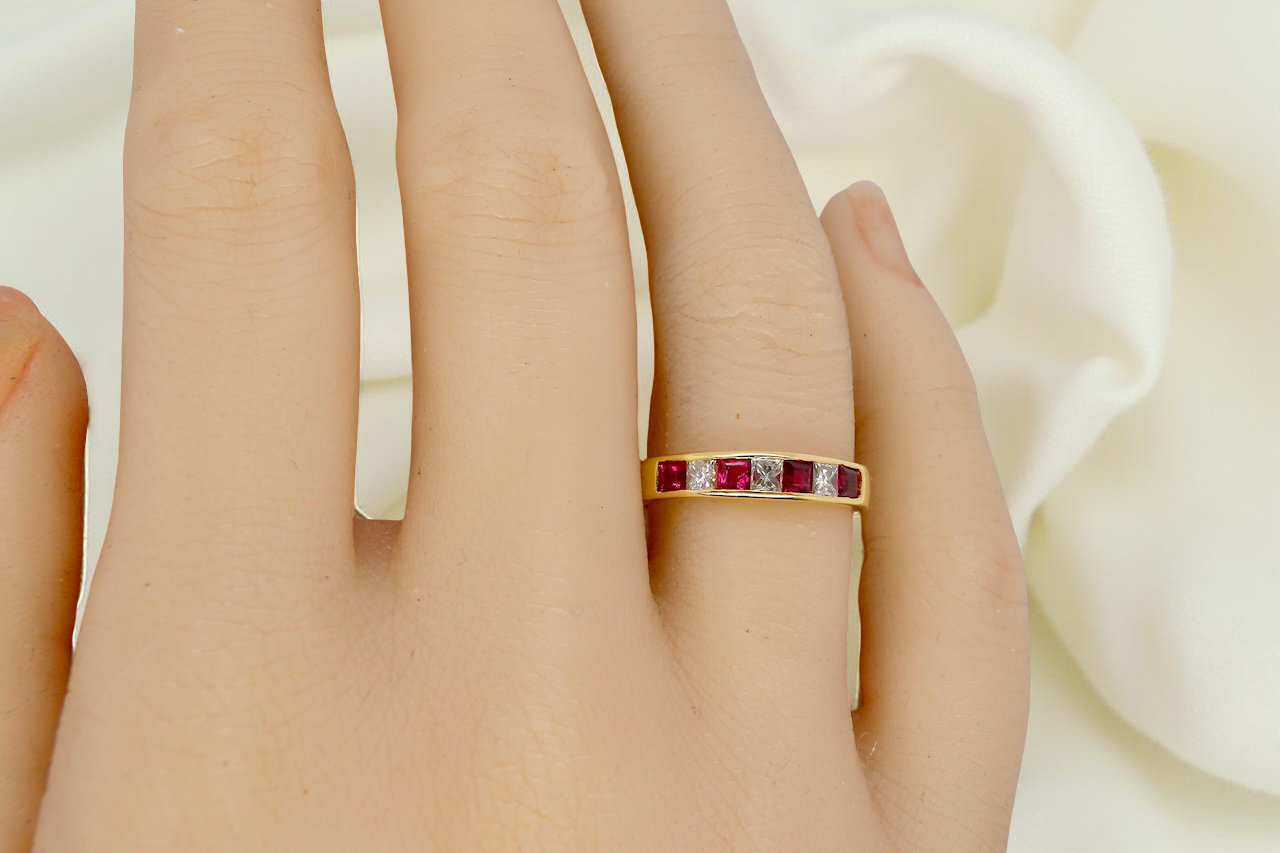 hand A beautiful 18-carat gold half-hoop eternity ring set with alternating rubies and diamonds.