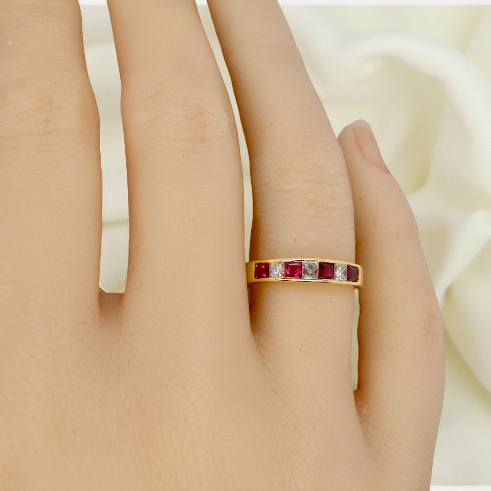 hand A beautiful 18-carat gold half-hoop eternity ring set with alternating rubies and diamonds.