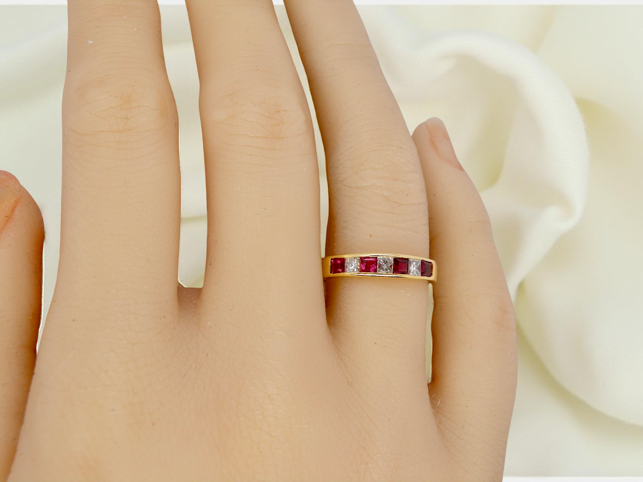 hand A beautiful 18-carat gold half-hoop eternity ring set with alternating rubies and diamonds.