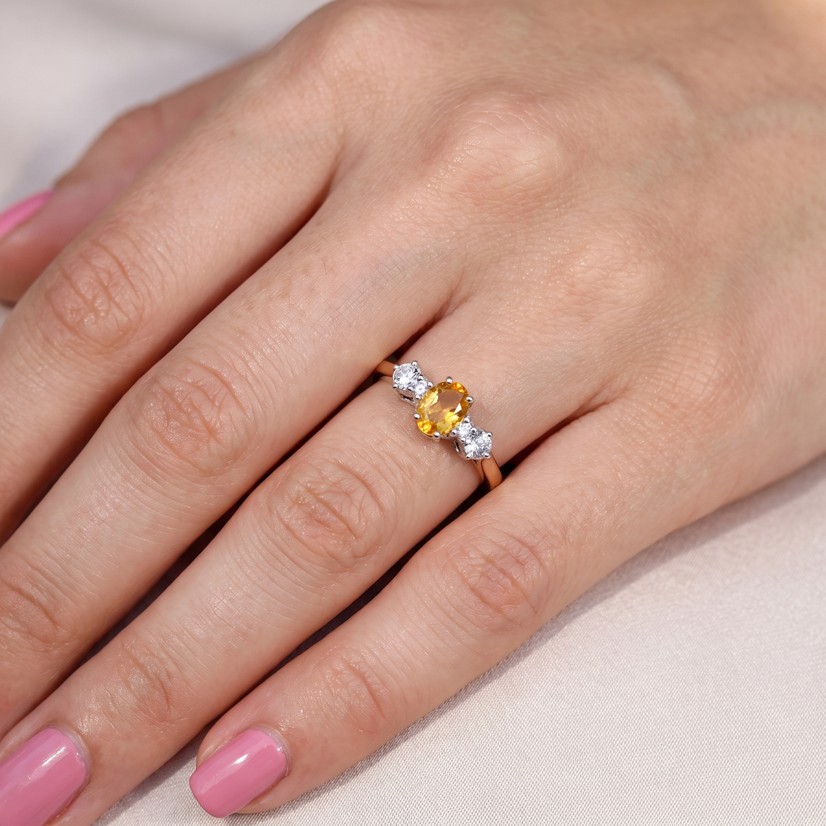 hand A beautiful 18 carat yellow gold trilogy ring, combining the warm golden tones of a yellow sapphire with white diamonds.