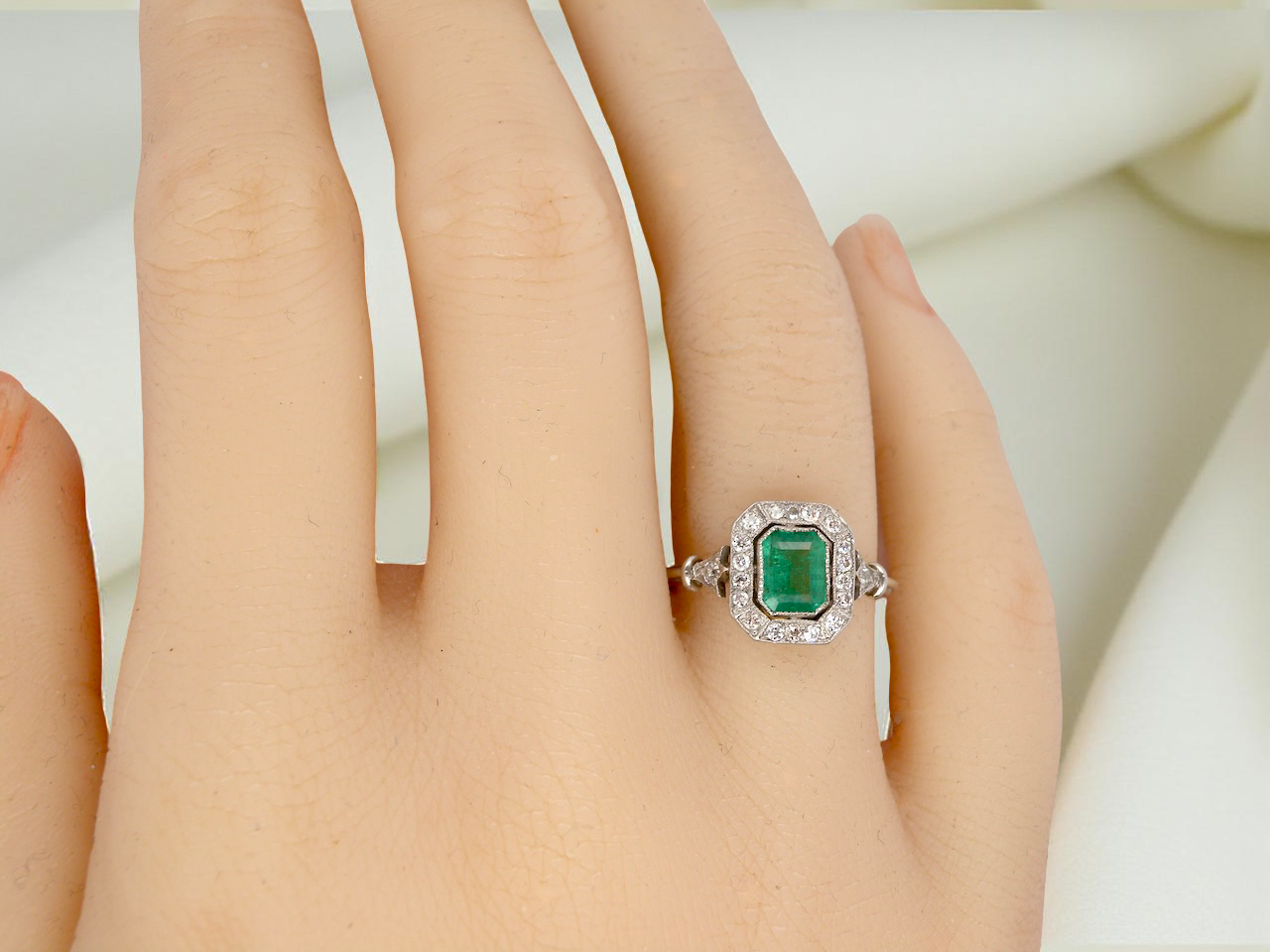 hand A beautiful Art Deco cluster ring centred with a vibrant step-cut emerald