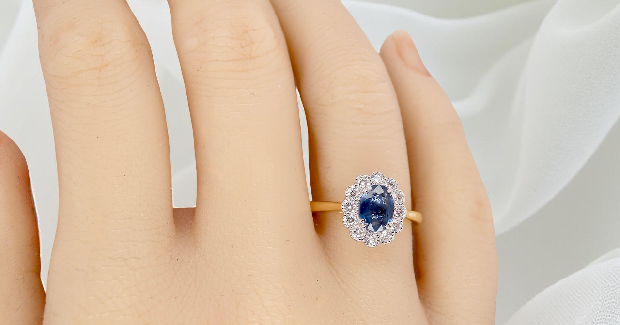 hand A beautiful cluster ring featuring an oval-cut mid to dark blue sapphire measuring 7 × 5 mm (approximately ¾ carat).