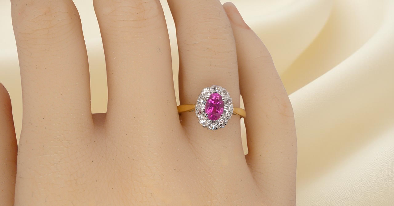 hand A beautiful vintage cluster ring showcasing a vivid pink sapphire centre stone, measuring approximately 6.6 × 4.3 mm(estimated 0.65 carats).