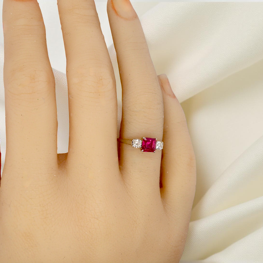 Ring with a red gemstone on a hand against a white background