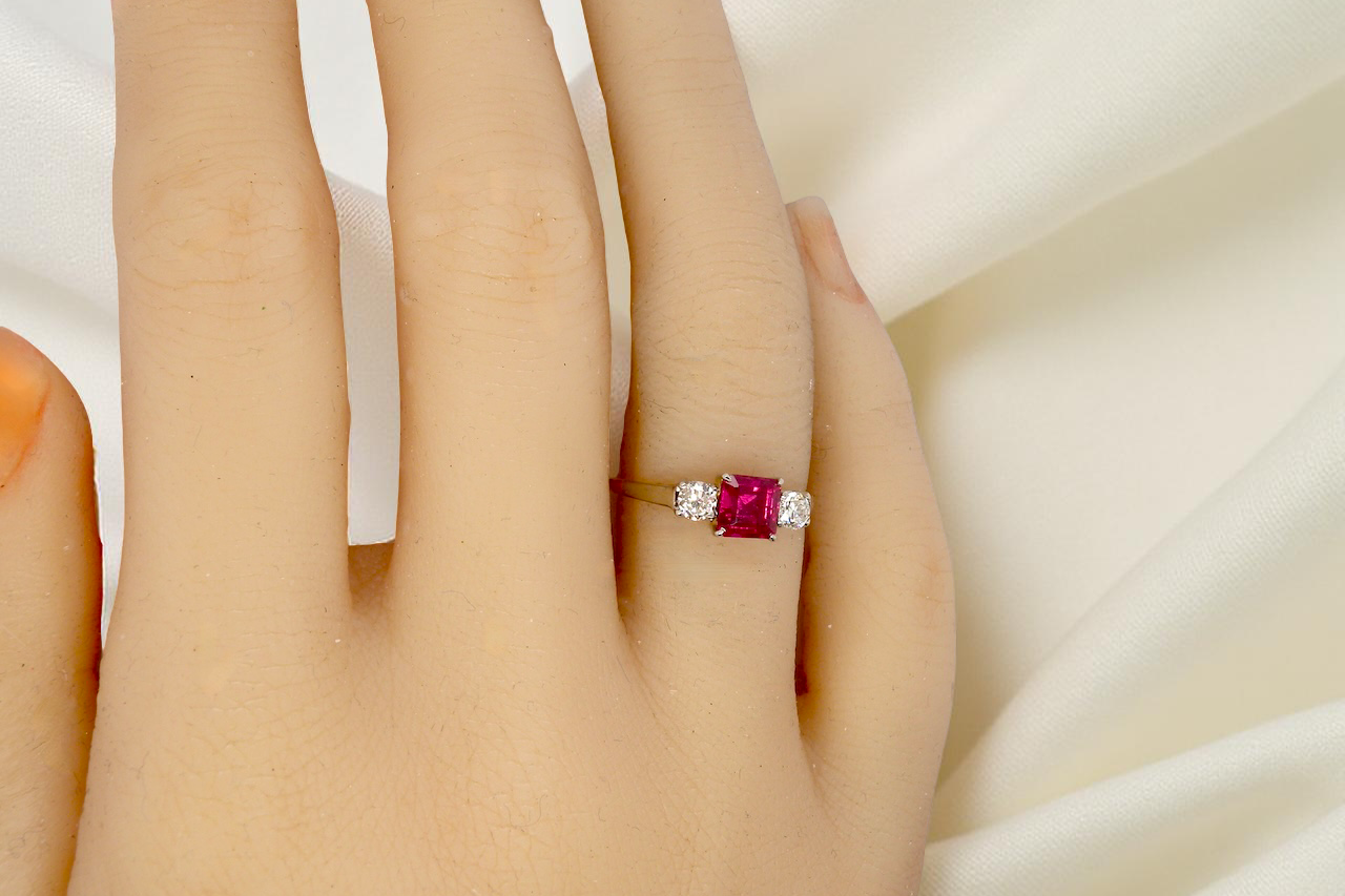 Ring with a red gemstone on a hand against a white background