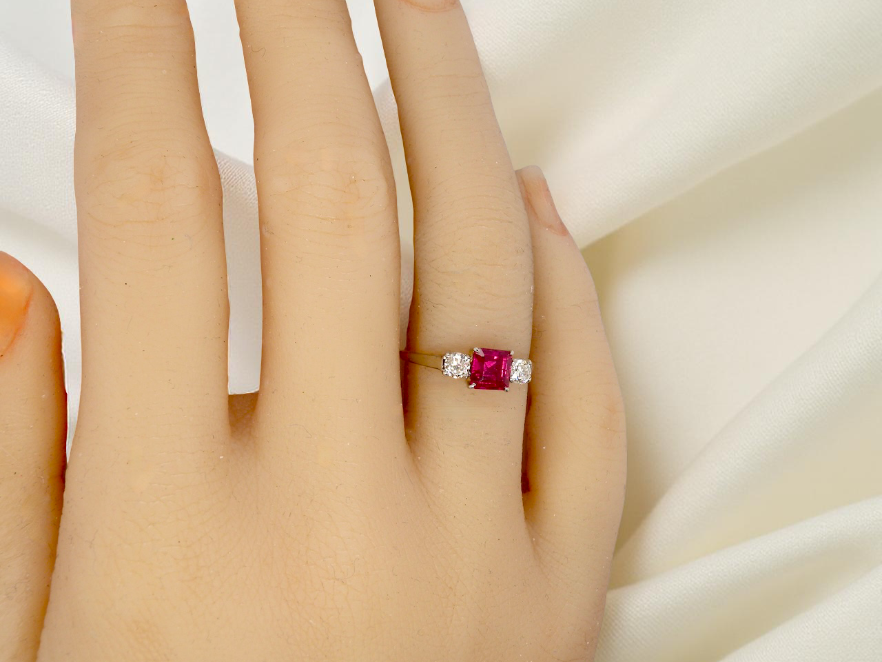Ring with a red gemstone on a hand against a white background