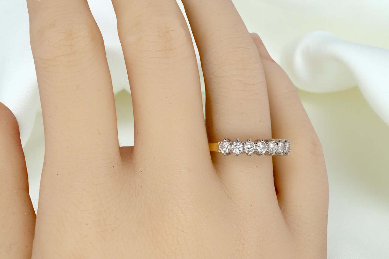 hand A fine 18 carat gold half hoop eternity ring, beautifully set with an array of seven brilliant-cut white diamonds.