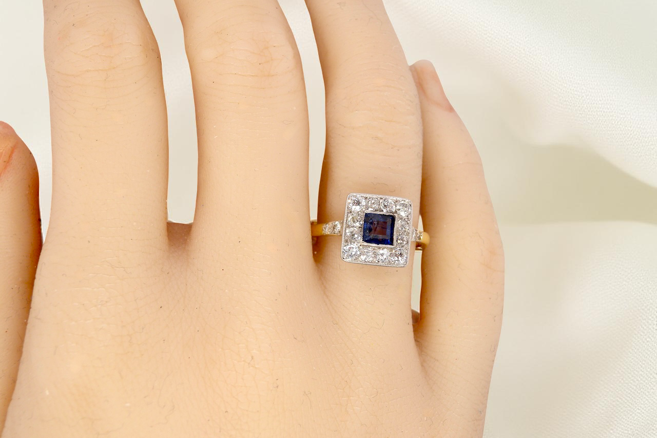 hand A fine Art Deco cluster ring. The centre stone a square sapphire 5x5mm (est 0.50 carats) in a mille grain setting.