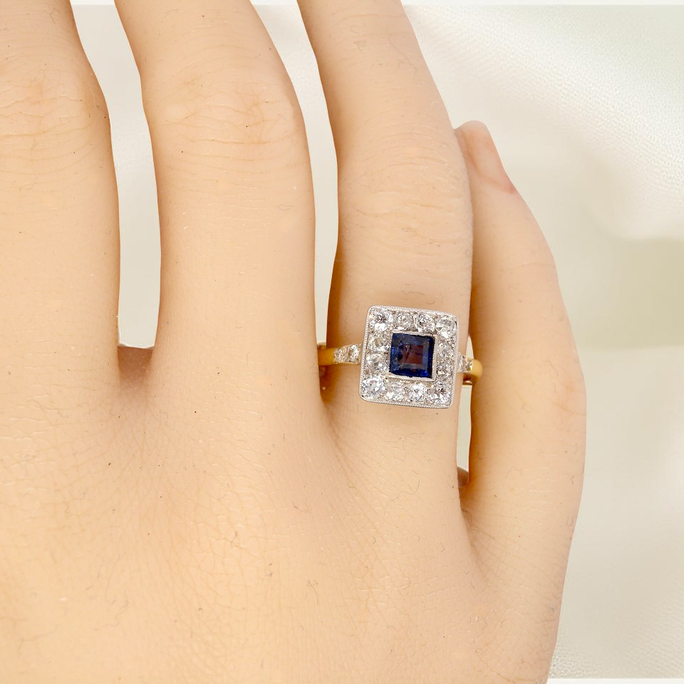 hand A fine Art Deco cluster ring. The centre stone a square sapphire 5x5mm (est 0.50 carats) in a mille grain setting.